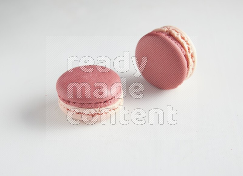 45º Shot of two Pink Litchi Raspberry macarons on white background