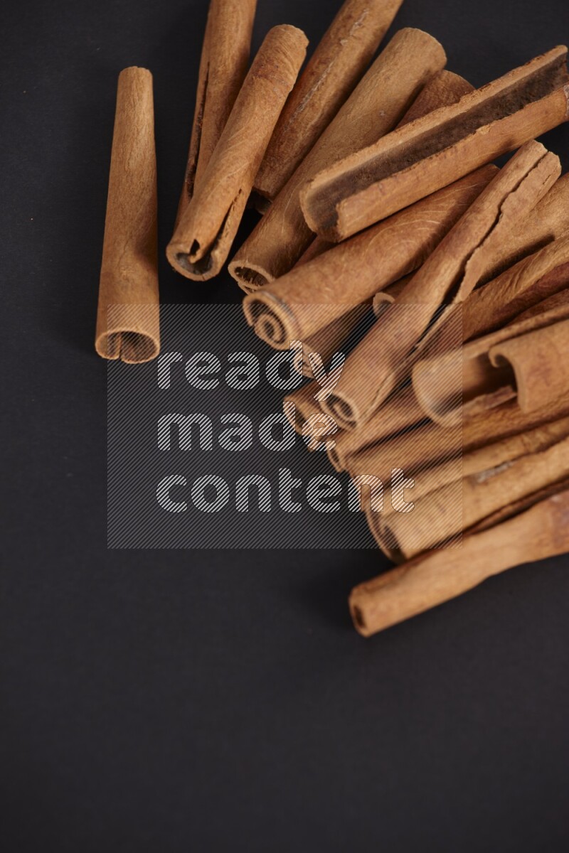 Cinnamon sticks stacked on black flooring