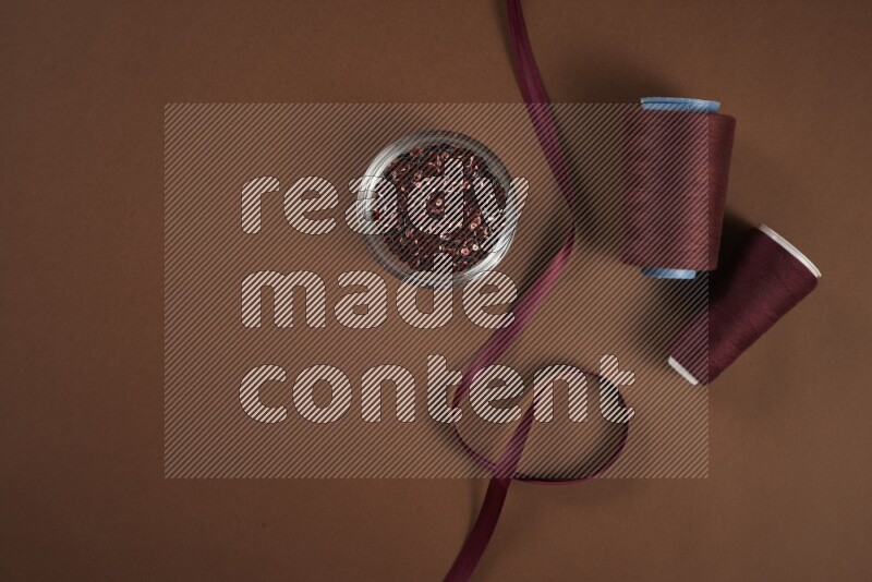 مجموعة من أدوات الخياطة والتفصيل حمراء اللون على خلفية بنية