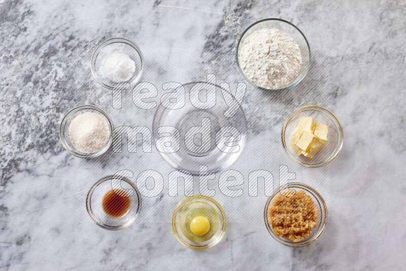 Cookies step by step with its ingredient, flour, butter, brown sugar, egg, vanilla extract, white sugar, chocolate chips and baking soda on grey marble background