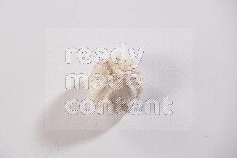 A whole garlic bulb placed on a white flooring