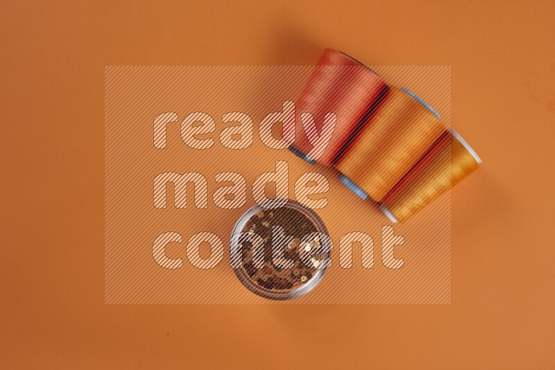 An orange collection of sewing and tailoring tools arranged on a orange background