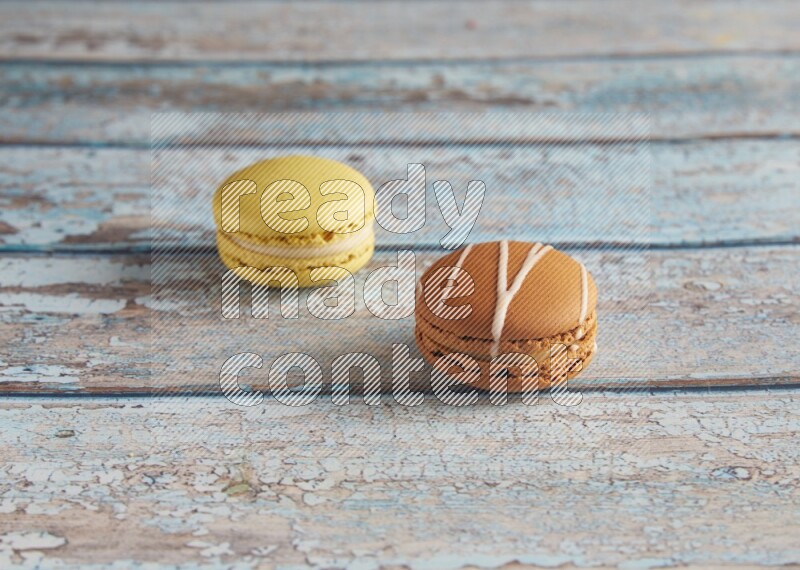 45º Shot of of two assorted Brown Irish Cream, and Yellow Lime macarons on light blue background