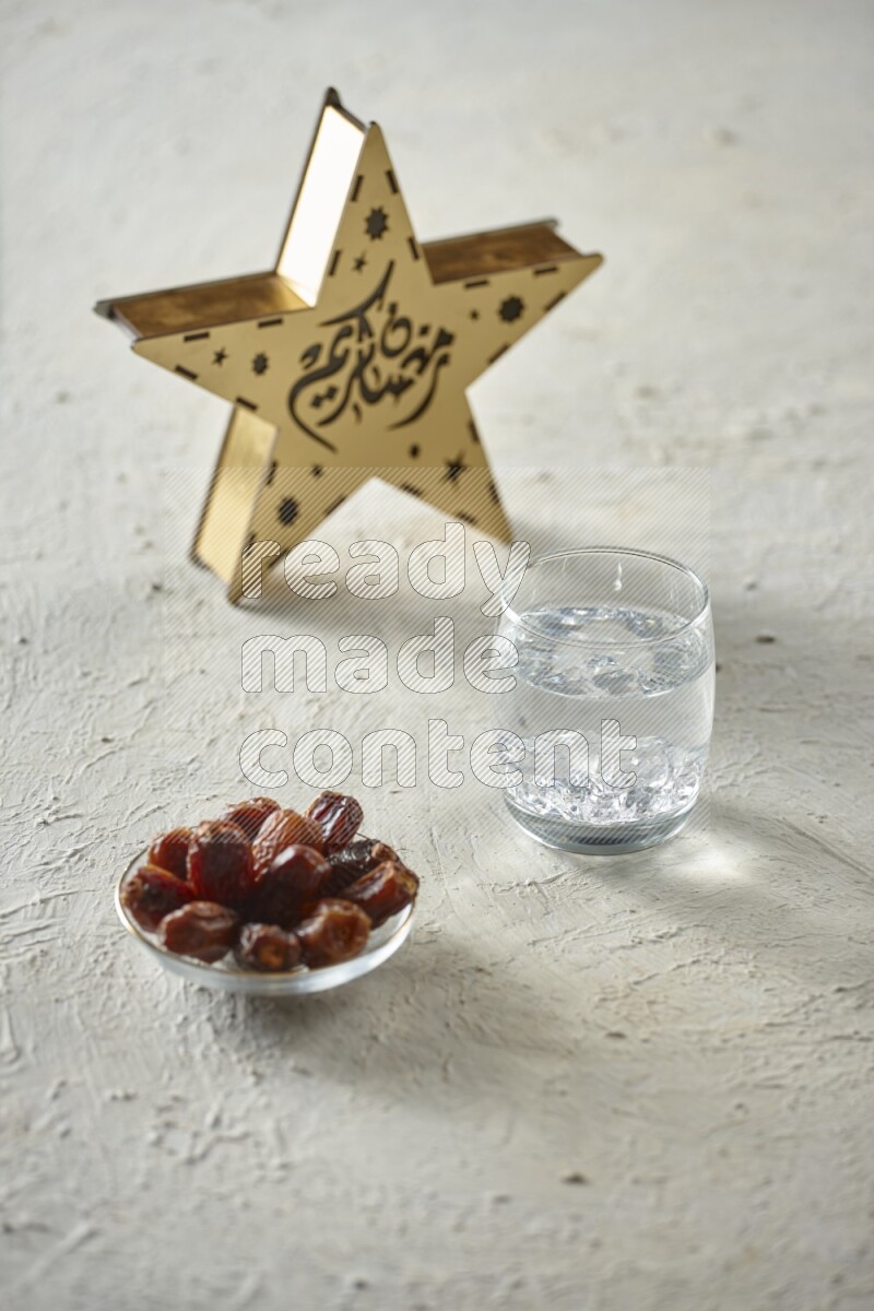 A wooden golden star lantern with different drinks, dates, nuts, prayer beads and quran on textured white background