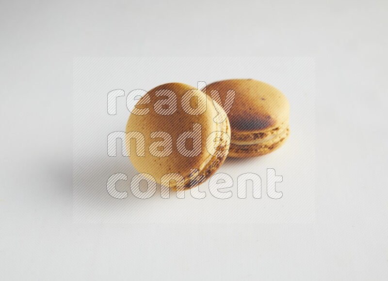 45º Shot of two Yellow Crème Brulée macarons on white background