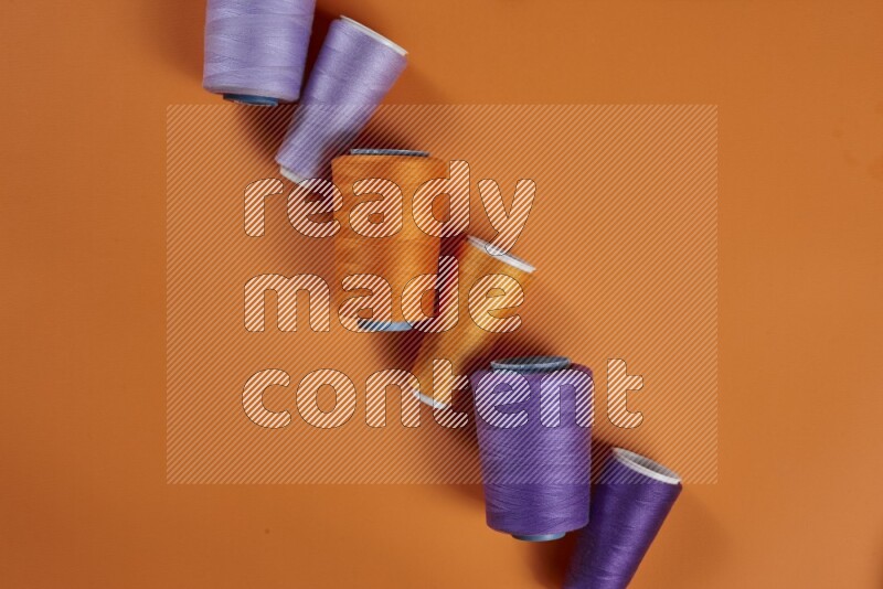 A purple collection of sewing and tailoring tools arranged on a orange background