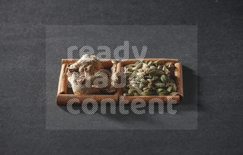 2 squares of cinnamon sticks full of cardamom and dried ginger on black flooring