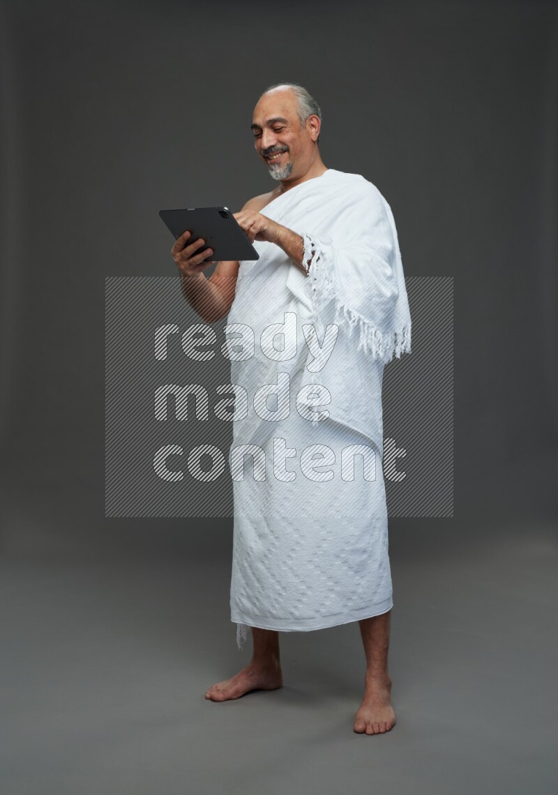 A man wearing Ehram Standing working on tablet on gray background