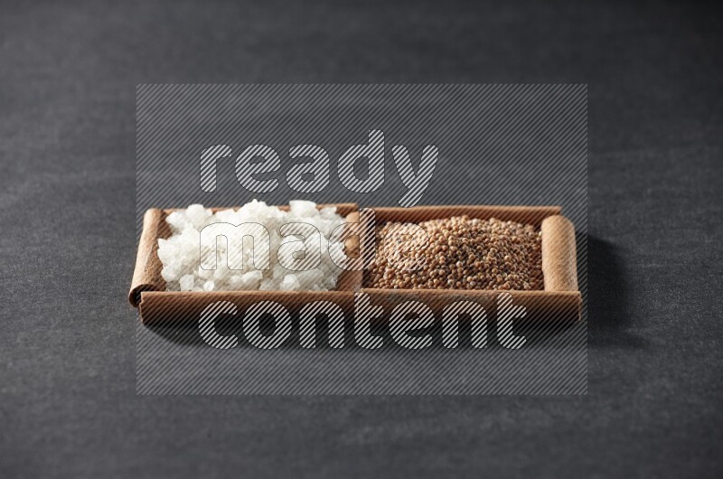 2 squares of cinnamon sticks full of mustard seeds and white salt on black flooring