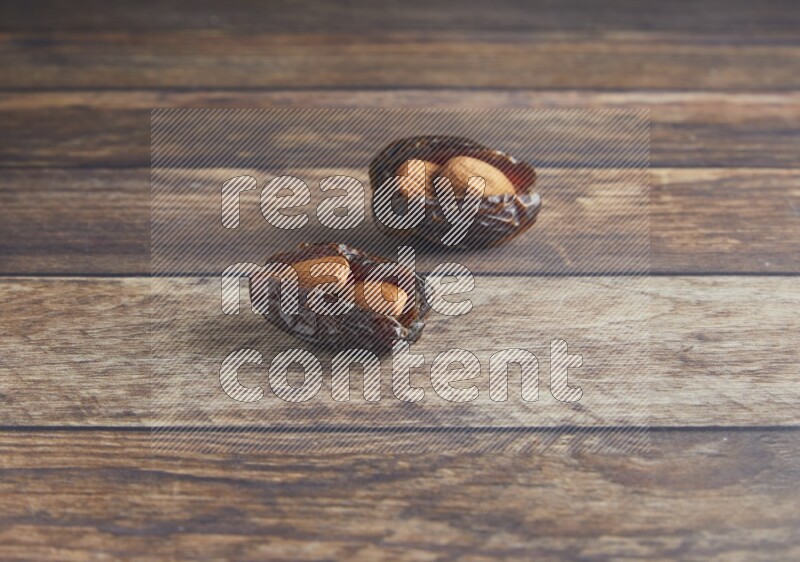 two almond stuffed madjoul dates on a wooden background