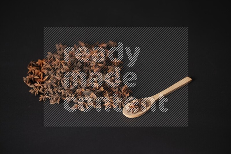 اليانسون النجمي في ملعقة خشبية ومتناثر على أرضية سوداء