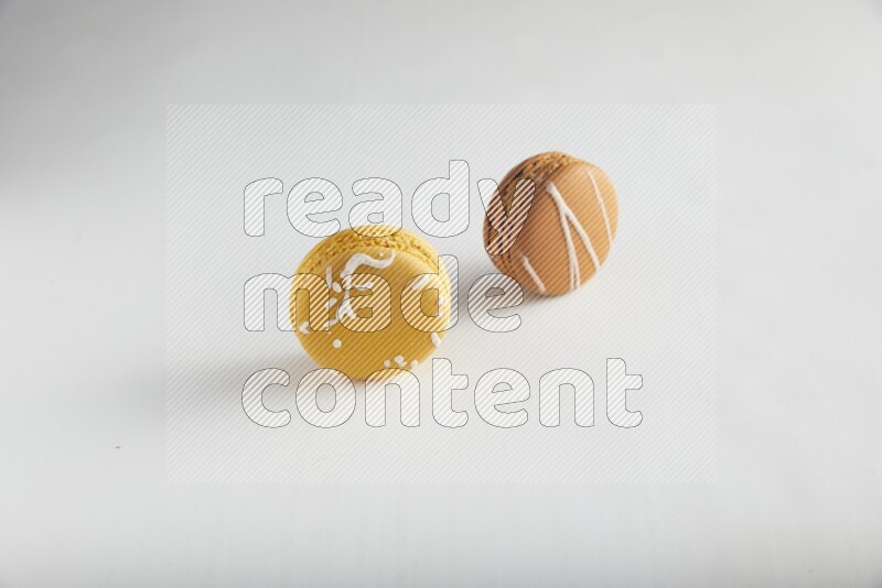 45º Shot of of two assorted Brown Irish Cream, and Yellow Piña Colada macarons on white background