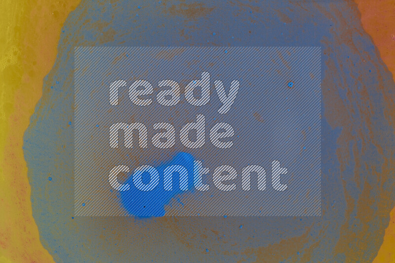 The image captures a dramatic splatter of blue paint over a orange backdrop