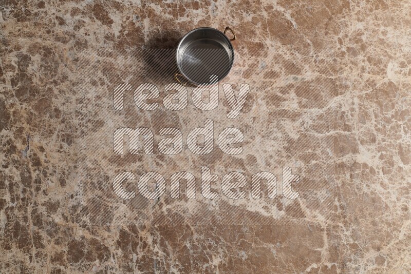 A small copper pot on beige marble background