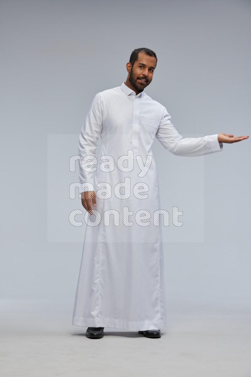 Saudi man Wearing Thob standing interacting with the camera on Gray background