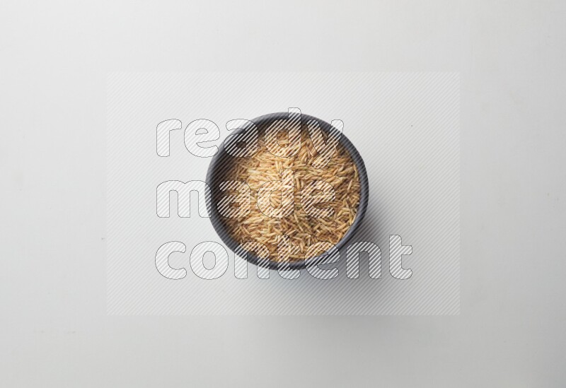 Top-view shot of long grain brown rice in a container on white background