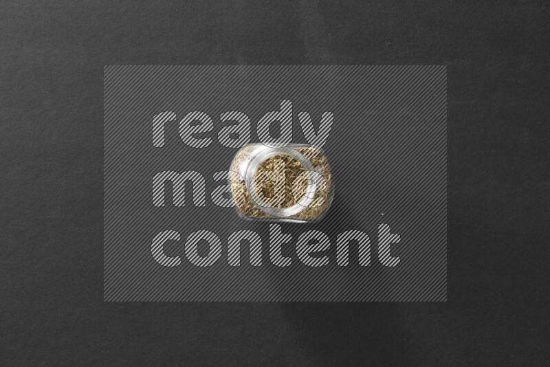 كمون في وعاء زجاجي علي خلفية سوداء