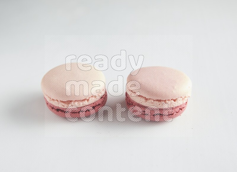 45º Shot of two Pink Litchi Raspberry macarons on white background