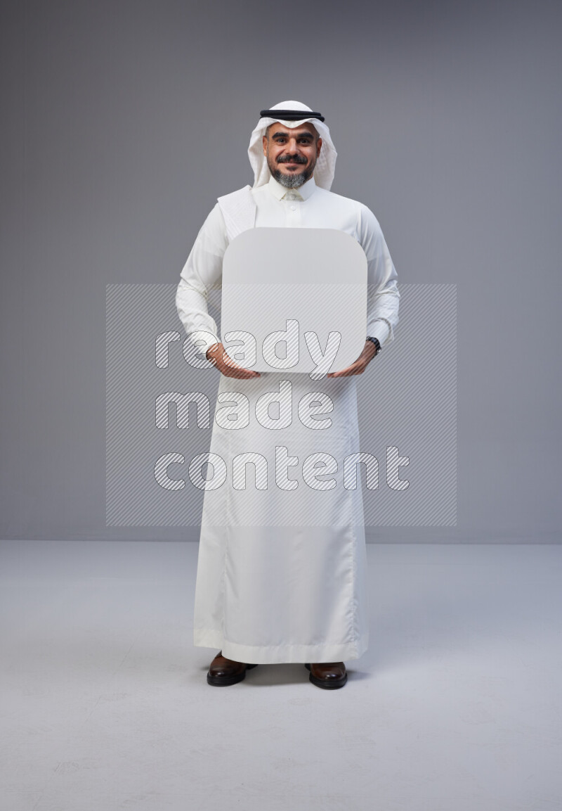 Saudi man Wearing Thob and white Shomag standing holding social media sign on Gray background