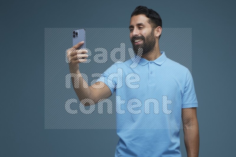 Man Taking a Selfie in a blue background wearing a Blue shirt