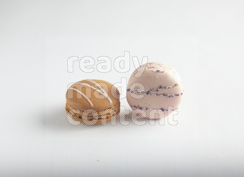 45º Shot of of two assorted Brown Irish Cream, and pink orange blossom macarons on white background