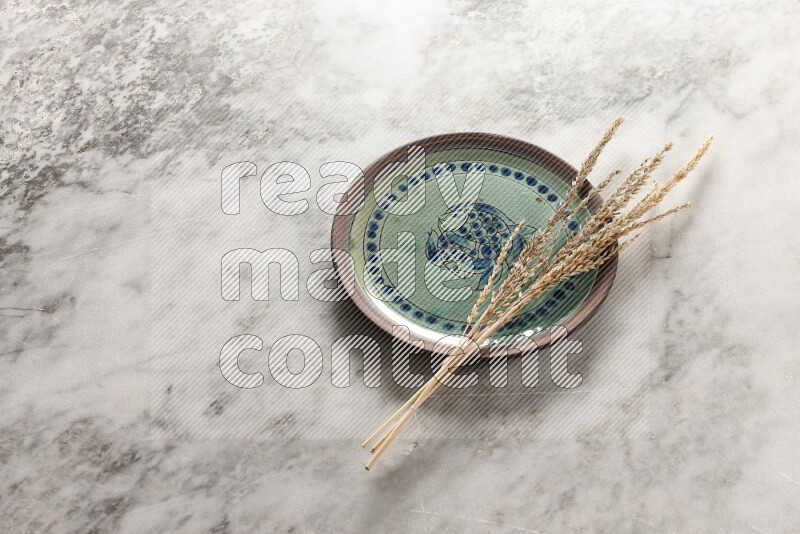 Wheat stalks on decorative pottery plate on grey marble background