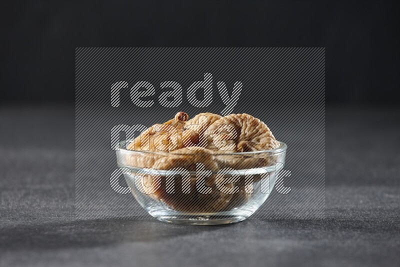 A glass bowl full of dried figs on a black background in different angles
