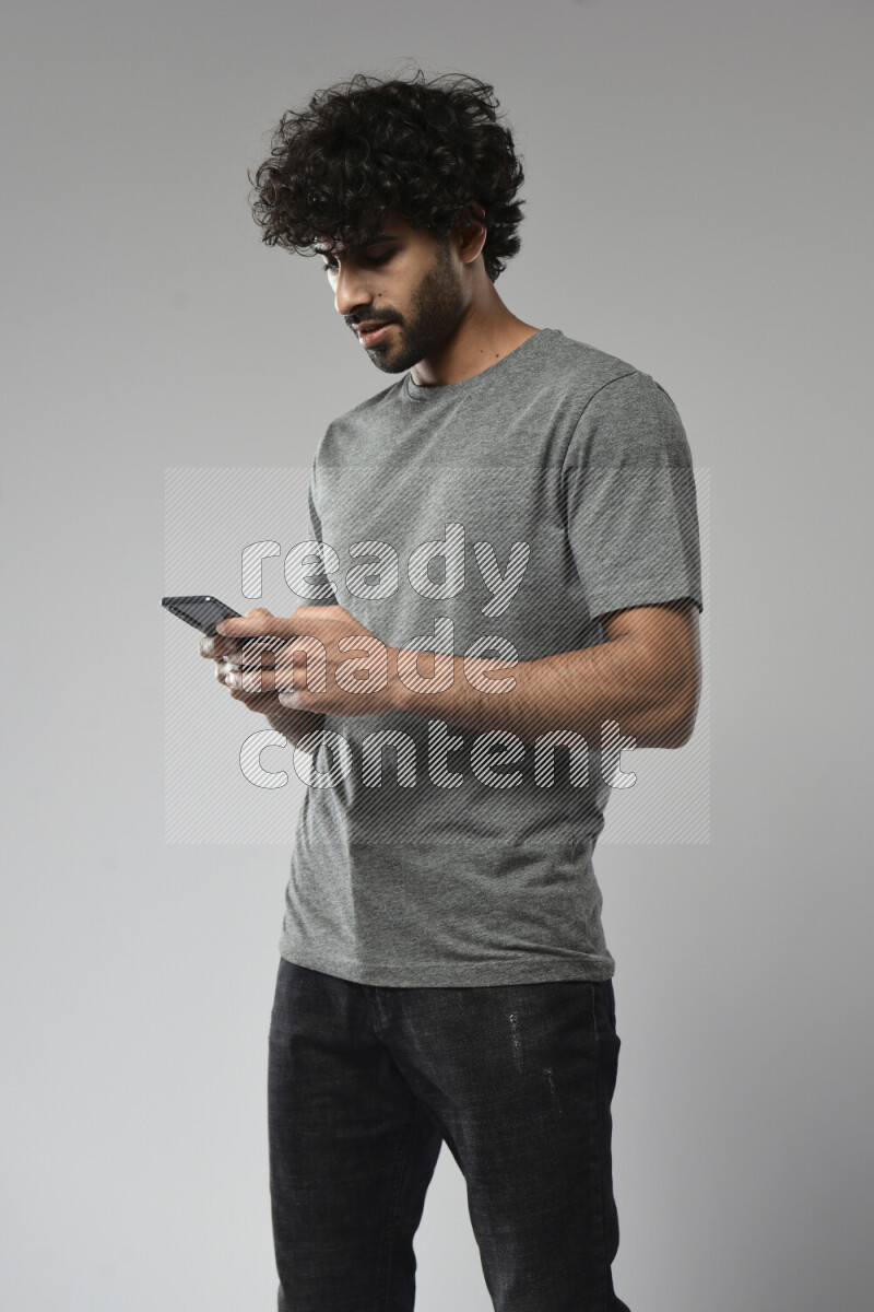 A man wearing casual standing and texting on the phone on white background
