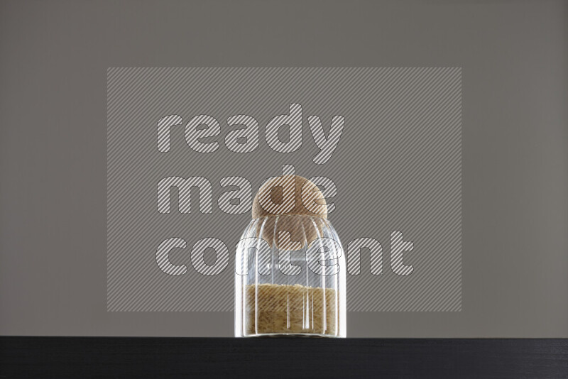 Basmati golden rice in a glass jar on black background