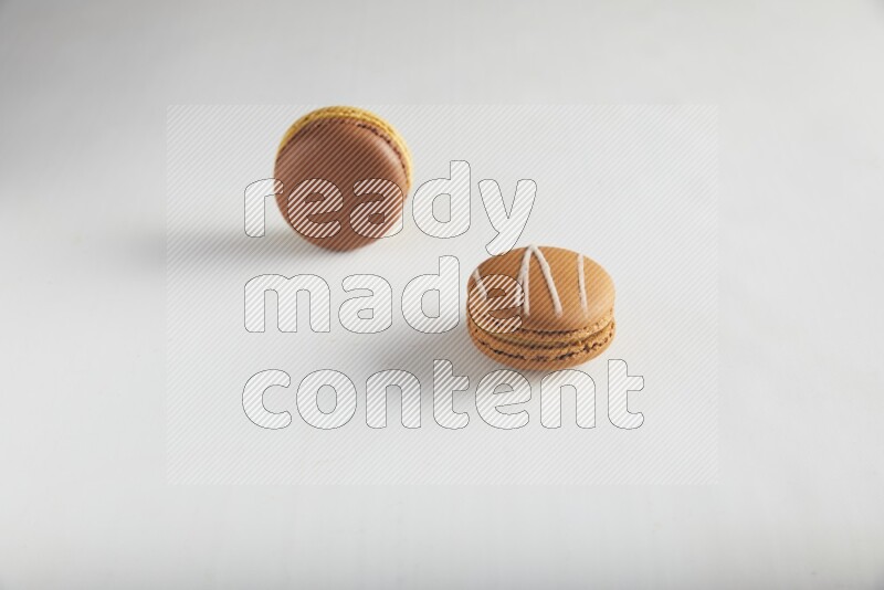 45º Shot of of two assorted Brown Irish Cream, and Yellow, and Brown Chai Latte macarons on white background
