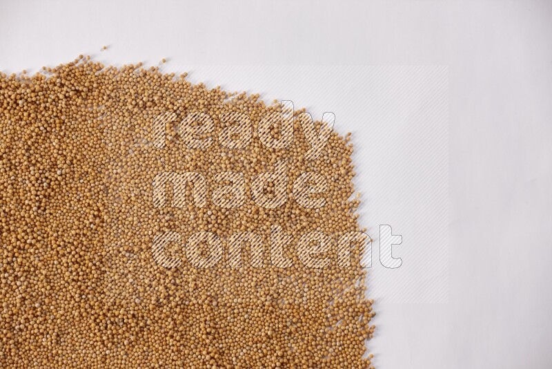 Mustard seeds spread on a white flooring