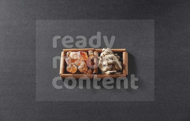 مربعان من أعواد القرفة ممتلئان بالزنجبيل المجفف والصمغ العربي علي خلفية سوداء