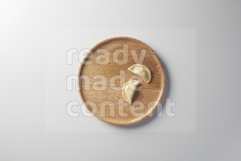 Two Sambosas on a wooden round plate on a white background