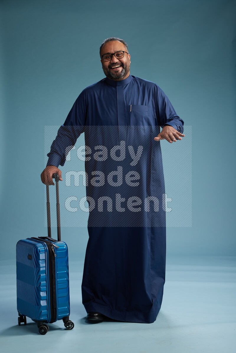 Saudi Man without shimag Standing pulling travel bag on blue background