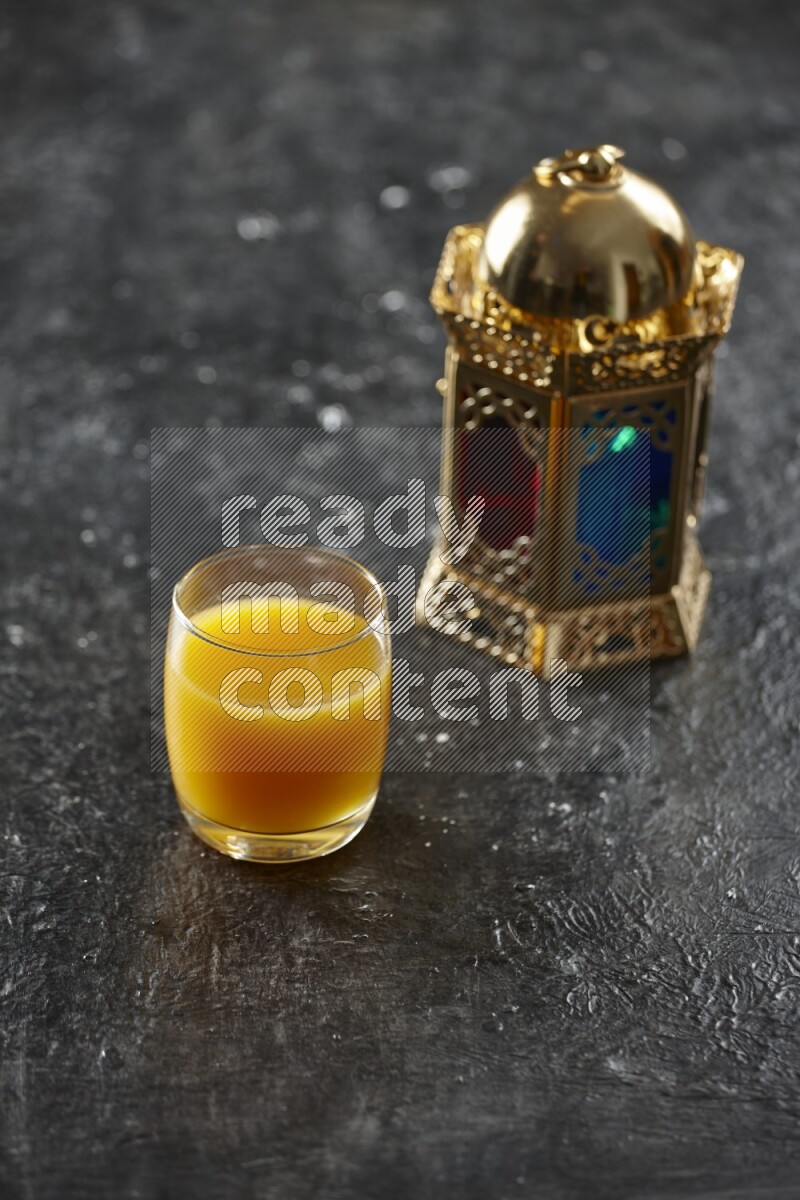 A golden lantern with different drinks, dates, nuts, prayer beads and quran on textured black background