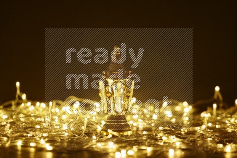A traditional ramadan lantern surrounded by glowing fairy lights in a dark setup