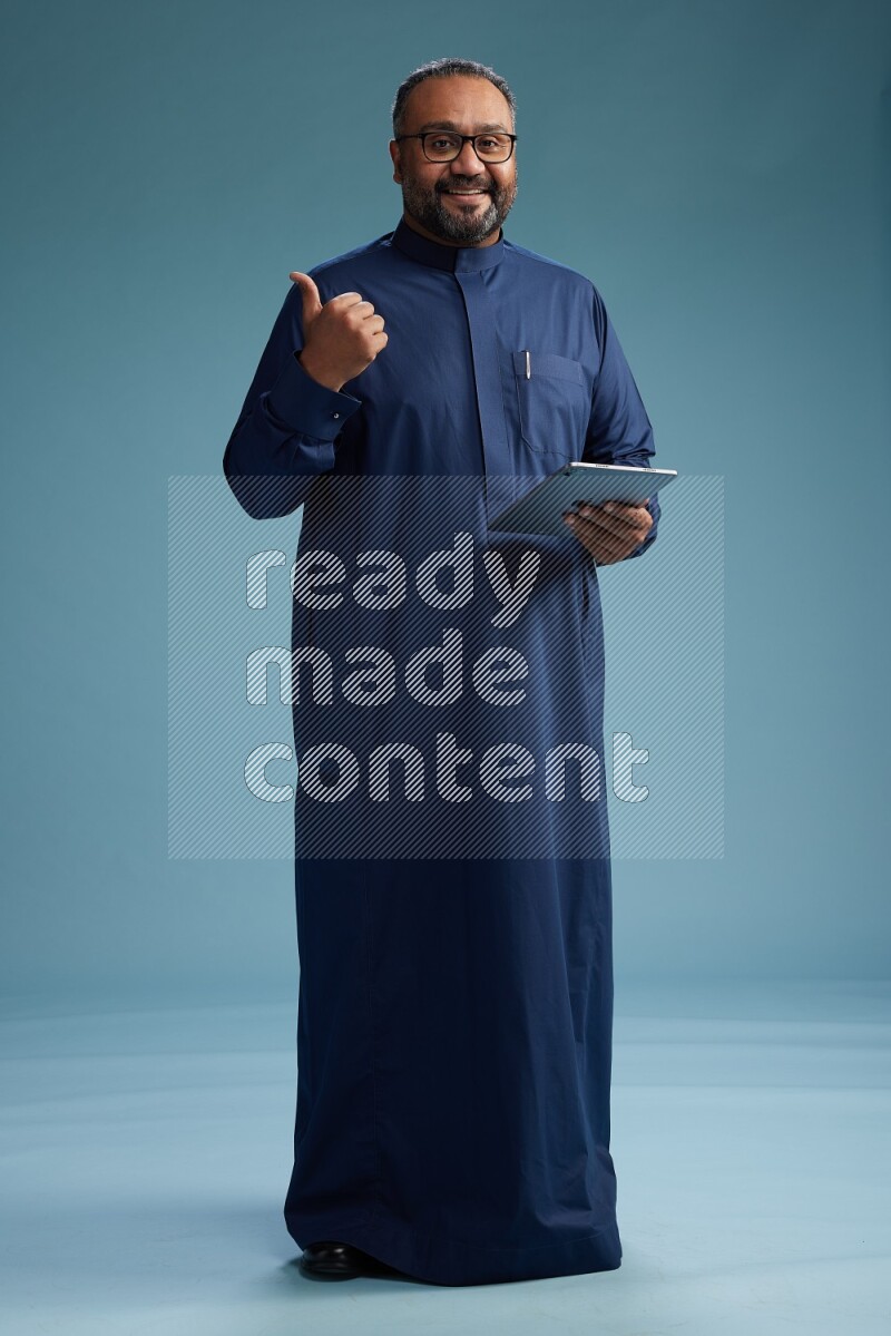 Saudi Man without shimag Standing working on tablet on blue background