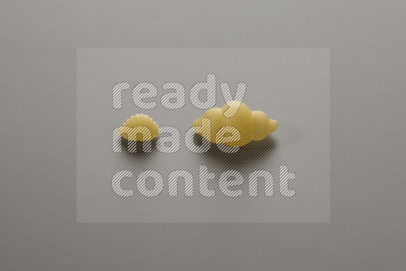 Shells pasta with other types of pasta on grey background