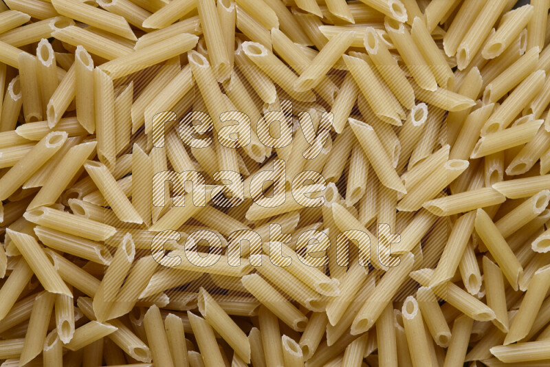 Mini penne pasta on grey background