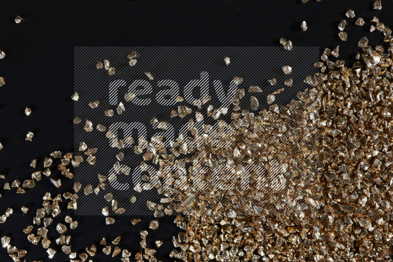Gold shimmering fragments of glass scattered on a black background