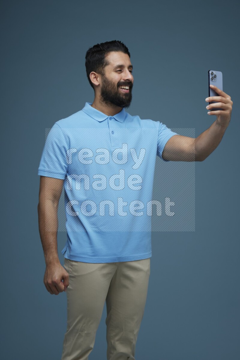 Man Taking a Selfie in a blue background wearing a Blue shirt