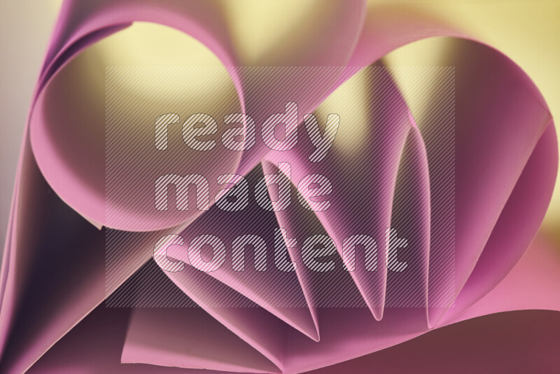 An artistic display of paper folds creating a harmonious blend of geometric shapes, highlighted by soft lighting in pink and warm tones
