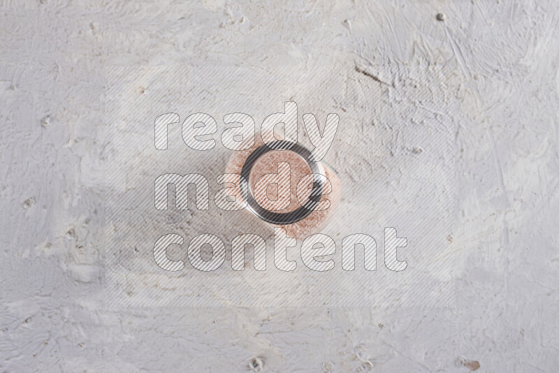 وعاء زجاجي ممتلئ بملح الهيمالايا الناعم على خلفية بيضاء