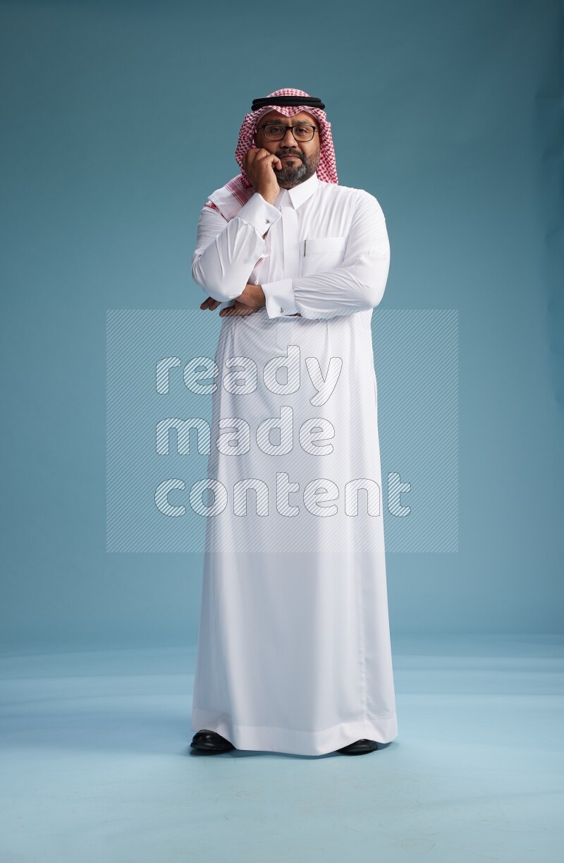 Saudi Man with shimag Standing Interacting with the camera on blue background