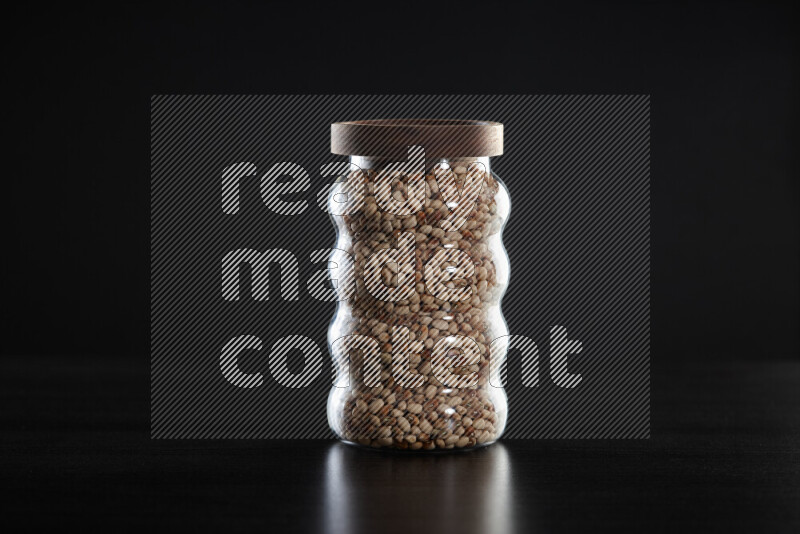 Black-eyed peas in a glass jar on black background