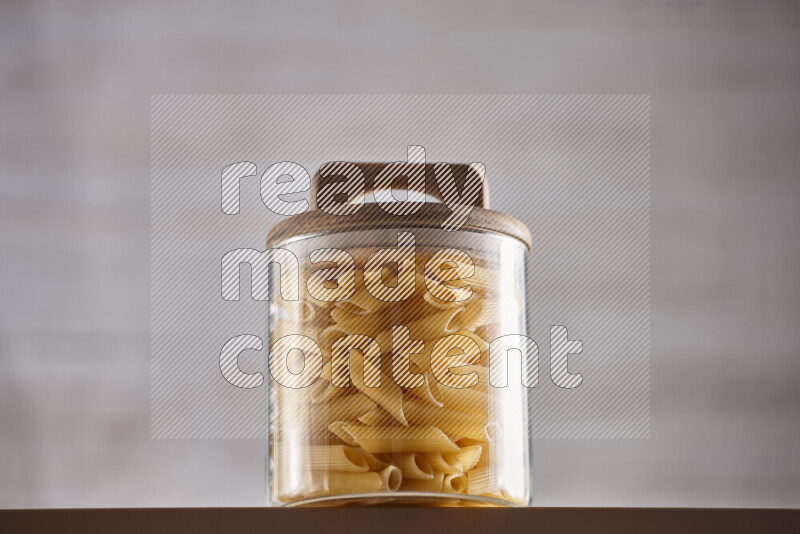 Raw pasta in glass jars on beige background