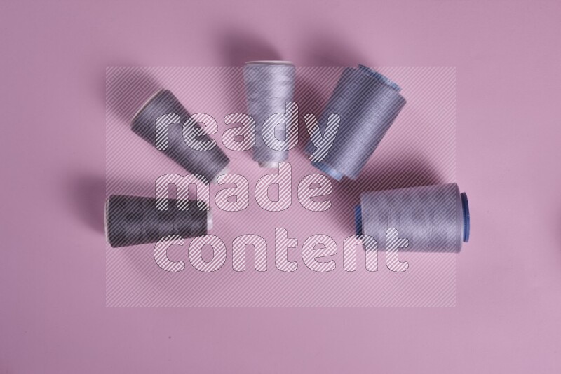 A grey collection of sewing and tailoring tools arranged on a pink background
