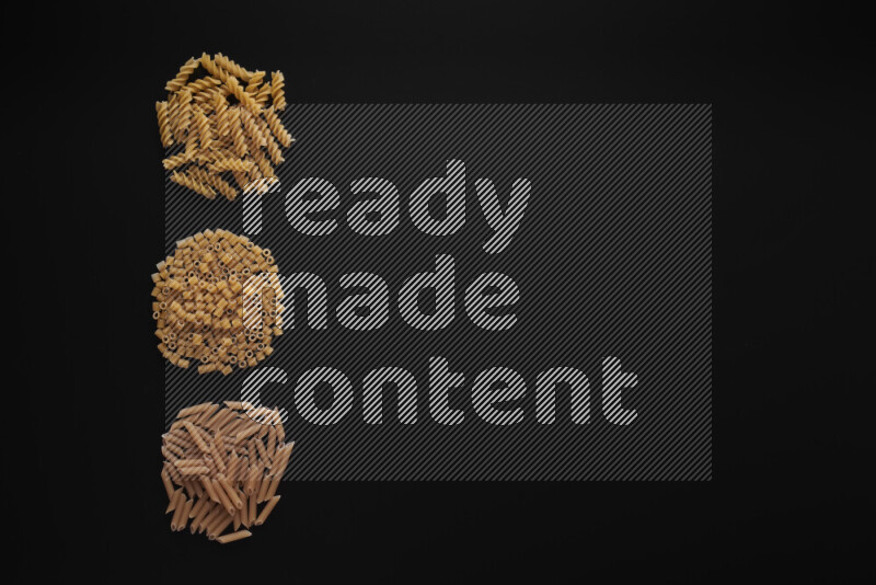 Different pasta types in 3 bunches on black background