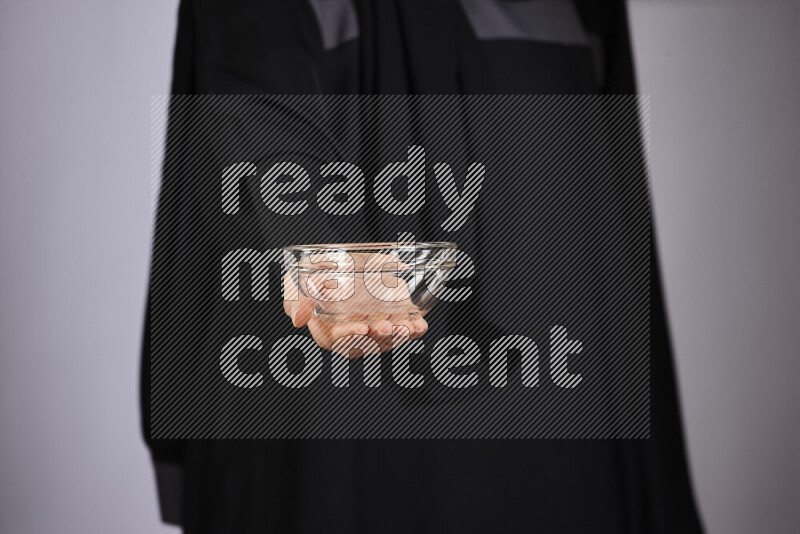 A woman in black abaya holding different glassware in different positions