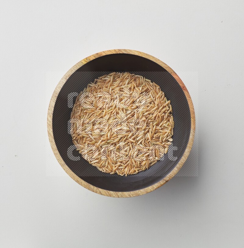 Top-view shot of long grain brown rice in a container on white background